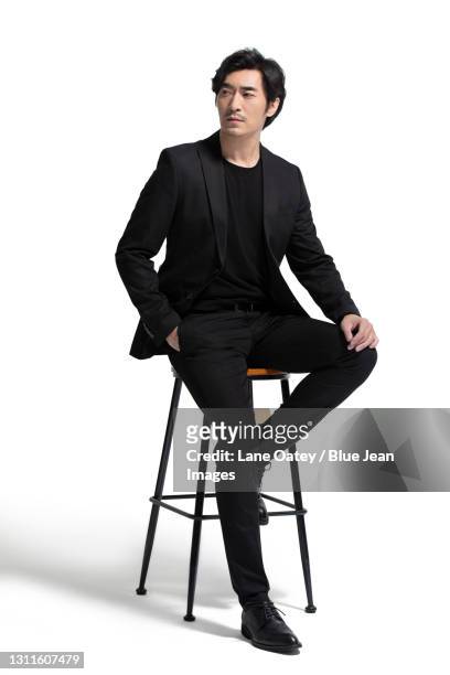 studio shot of fashionable mid adult man - sedersi posizione fisica foto e immagini stock