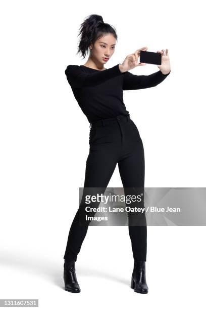 fashionable young woman using smart phone - taking selfie white background stock-fotos und bilder