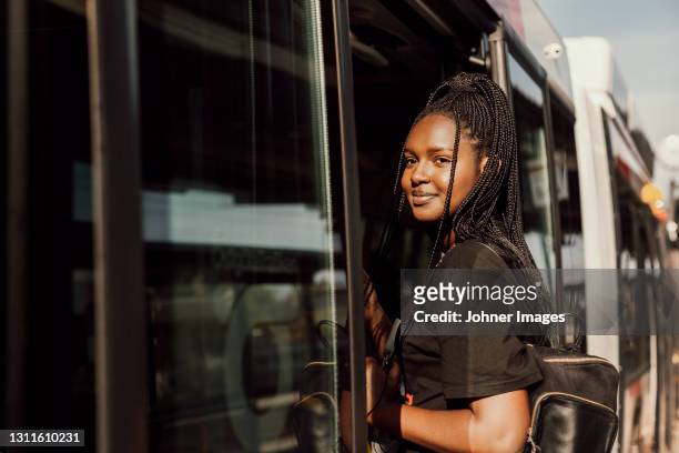 young woman entering bus - bus stock-fotos und bilder