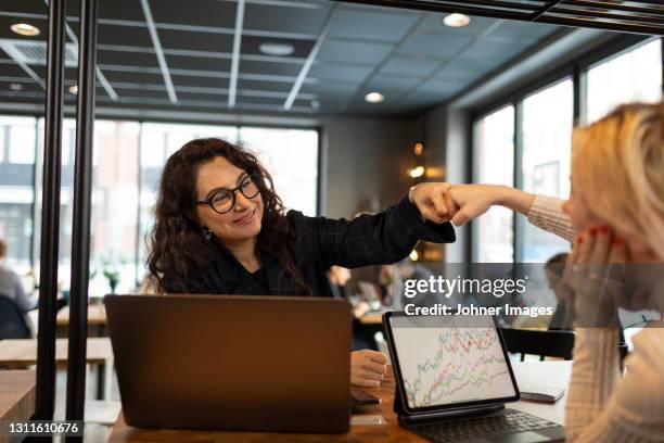 female coworkers doing fist bump - team business high 5 stock pictures, royalty-free photos & images
