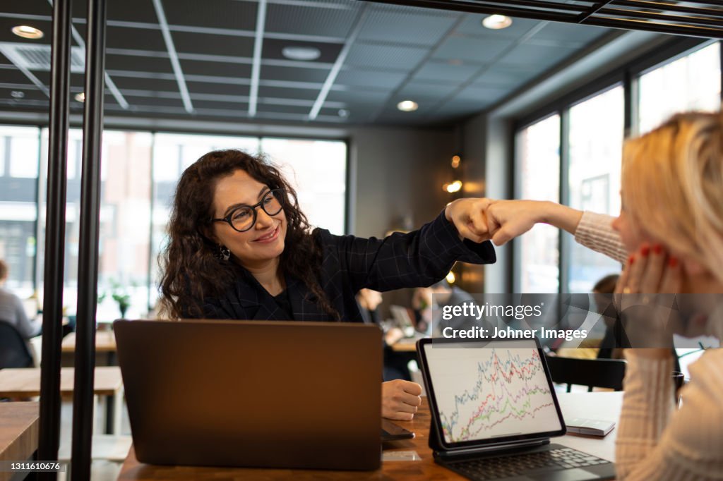 Female coworkers doing fist bump