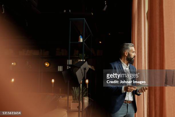 businessman in cafe holding digital tablet - looking through window stockfoto's en -beelden