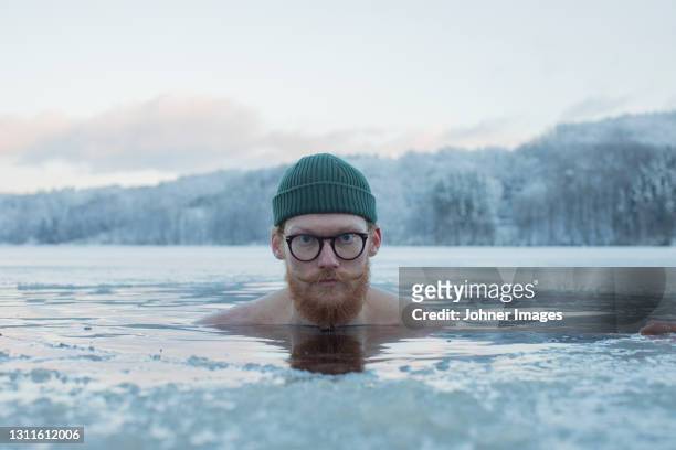 man swimming in frozen lake - koud stockfoto's en -beelden