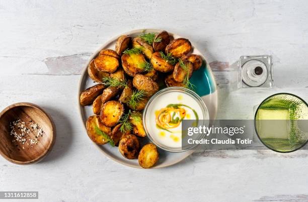 roasted potatoes and a bowl of dipping sauce on a plate on white background - prepared potato stock-fotos und bilder