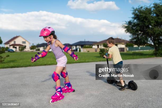 kids playing together on skates and kick scooter - roller skates stock-fotos und bilder