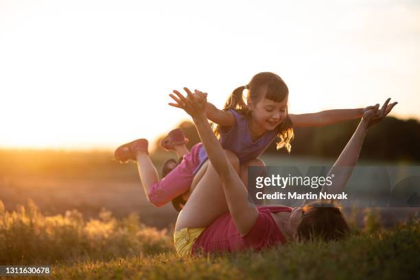 mother lifting her little girl in the air - night picnic stock pictures, royalty-free photos & images
