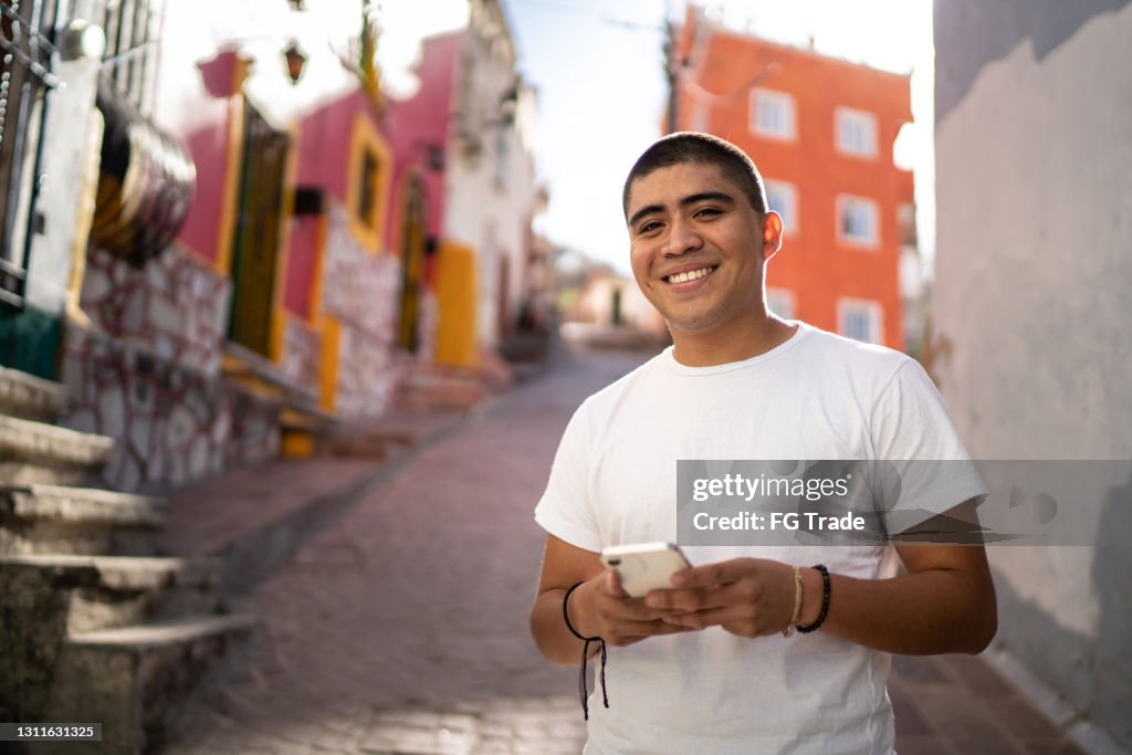 Porträt eines jungen Mannes mit Smartphone auf der Straße