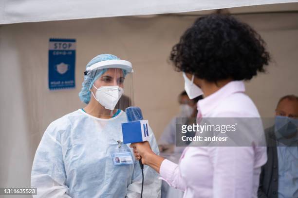 journalist interviewing a healthcare worker working at a covid-19 vaccination stand - journalism stock pictures, royalty-free photos & images