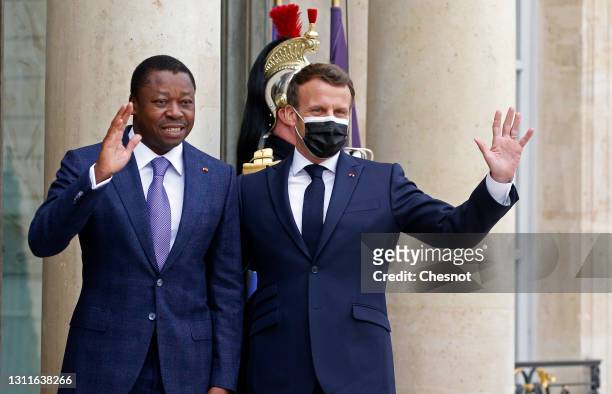 French President Emmanuel Macron wearing a protective face mask and Togolese President Faure Essozimna Gnassingbe wave to media prior to their...