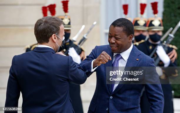 French President Emmanuel Macron wearing a protective face mask elbow bumps with Togolese President Faure Essozimna Gnassingbe prior to their working...