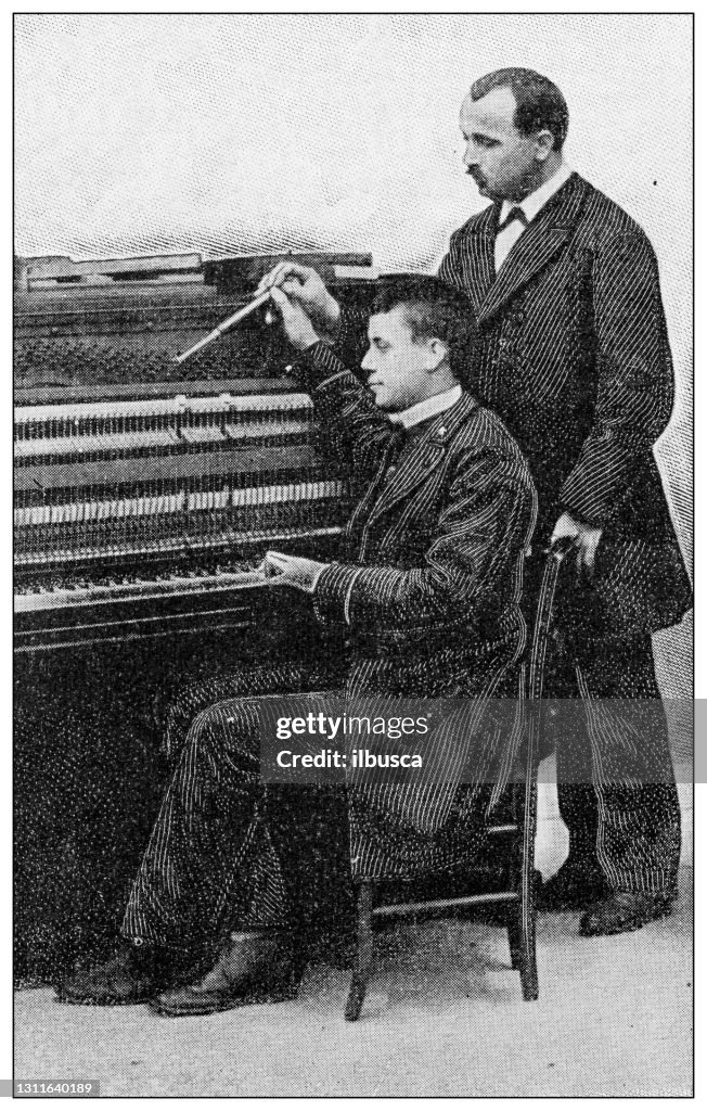 Antique black and white photograph: Blind man learning tuning piano