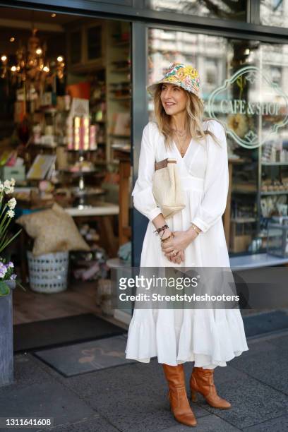 Fashion designer Sue Giers wearing brown knee high boots by Celine, a long white longsleeve dress by SoSUE, a multicolor floral print hat by...