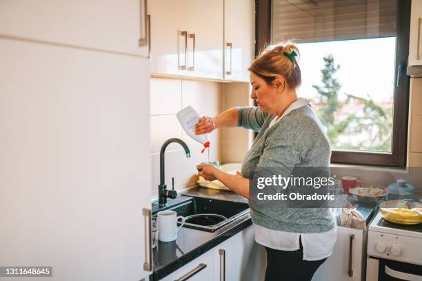 ama de casa mayor lavando los platos - madre ama de casa fotografías e imágenes de stock