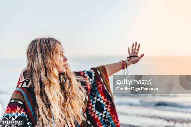 young long-haired woman meditates / prays on beach. serenity moments. - voyage zen stock pictures, royalty-free photos & images
