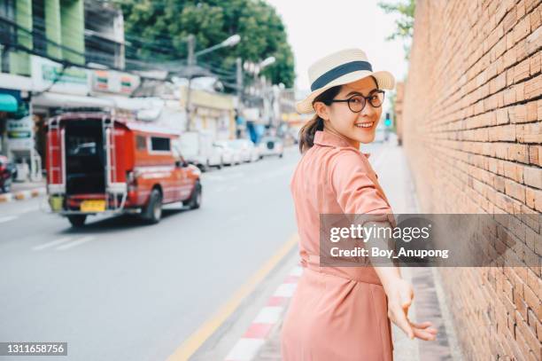 portrait of young asian tourist woman walking nearly the ancient brick walls of chiang mai province of thailand. - chiang mai province stock-fotos und bilder