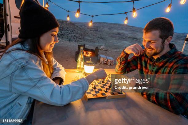 junges paar camping spielen schach zusammen an einem picknicktisch mit ihrem hund, closeup - windlicht stock-fotos und bilder