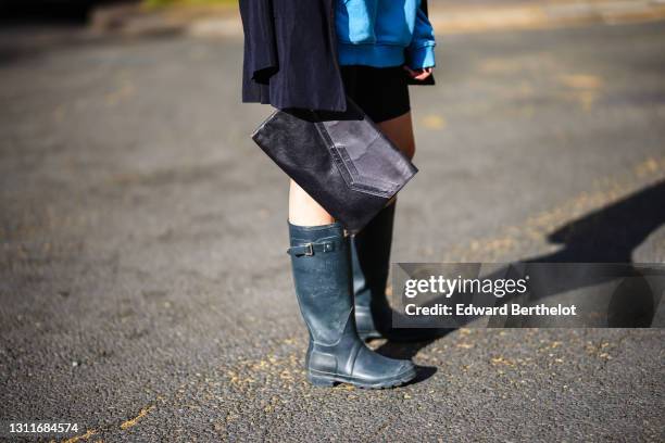 Emy Venturini @sustainably_by_emy wears a clutch, short leggings from Alesia, knee high dark green rubber rain boots from Hunter, on April 06, 2021...