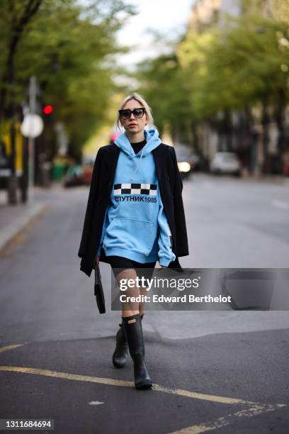 Emy Venturini @sustainably_by_emy wears sunglasses from Dita, a blue hoodie sweater with printed black and white checked logo and Russian words from...