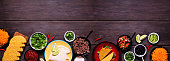 Taco bar bottom border with assorted ingredients on a dark wood banner background. Copy space.