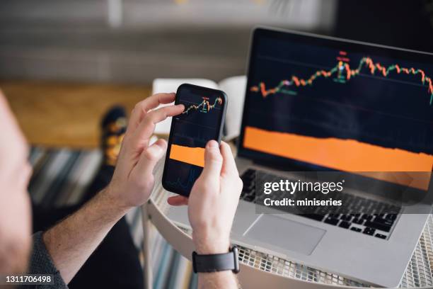 work at home: man analyzing crypto graph on laptop screen - mercado imagens e fotografias de stock