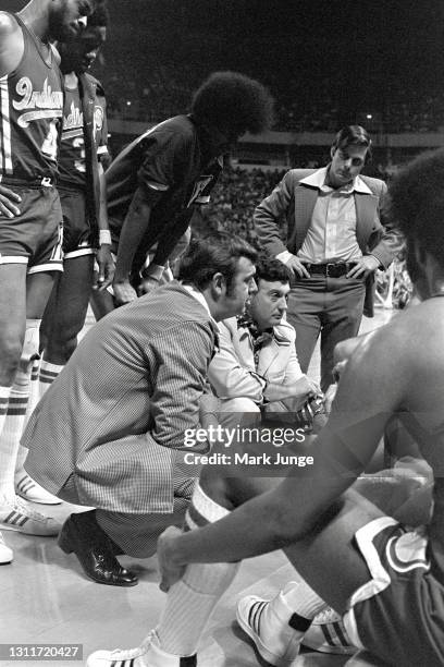 Indiana Pacers coach William Robert “Slick” Leonard and assistant coach Jerry Oliver kneel in a team huddle during an ABA basketball game against the...