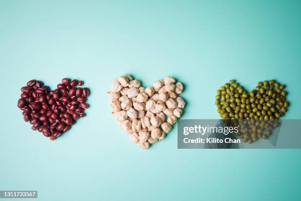 overhead view of heart-shaped adzuki beans, chickpeas and mung beans - adzuki bean stock pictures, royalty-free photos & images