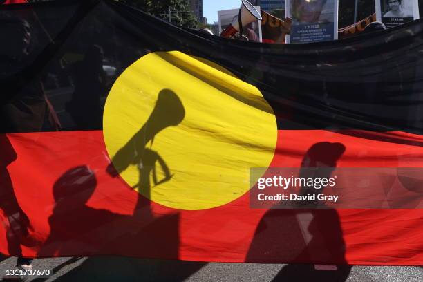 Protesters are seen through an Aboriginal flag during a rally on April 10, 2021 in Sydney, Australia. The national day of action marks 30 years since...