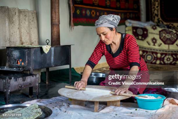 local woman rolling dough on ground in multi-purpose room. - azerbaijan food stock pictures, royalty-free photos & images