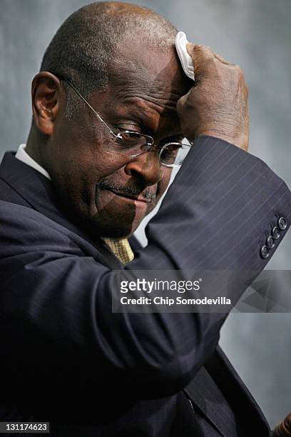 Republican presidential candidate and former CEO of Godfather's Pizza Herman Cain wipes his brow while participating in a discussion with members of...
