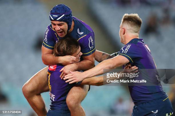 Ryan Papenhuyzen of the Storm celebrates scoring a try with team mates Jahrome Hughes and Cameron Munster during the round five NRL match between the...