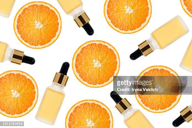 beauty pattern made of vitamin c serum in cosmetic bottle with dropper and slices of orange - vitamin c stock-fotos und bilder