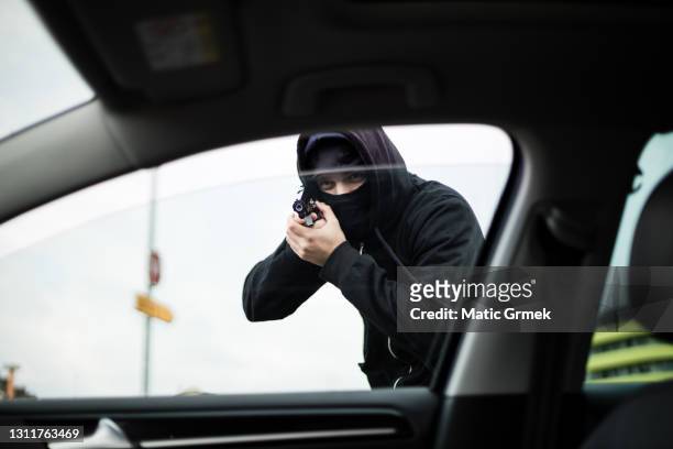 robber pointing a gun at a driver - kidnapping imagens e fotografias de stock