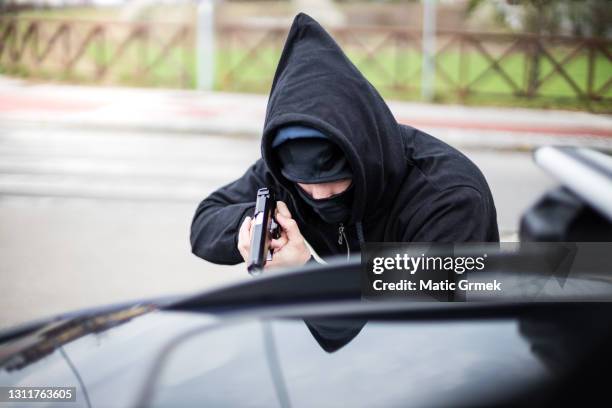 robber pointing a gun at a driver - hijack imagens e fotografias de stock