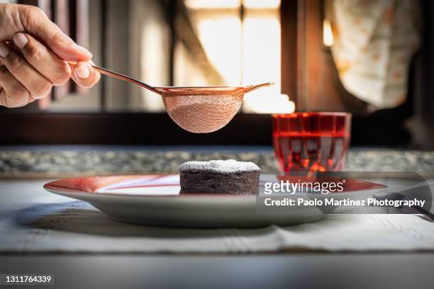woman sprinkling powdered sugar on chocolate soufflé - chocolate souffle stock pictures, royalty-free photos & images
