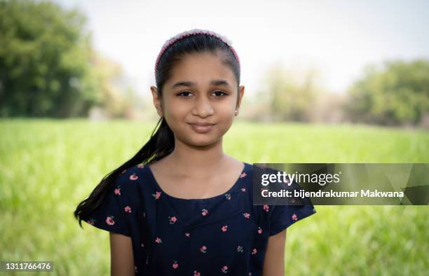 indian teenager girl standing in grassy field and looking at the camera. - 12 year old indian girl stock pictures, royalty-free photos & images