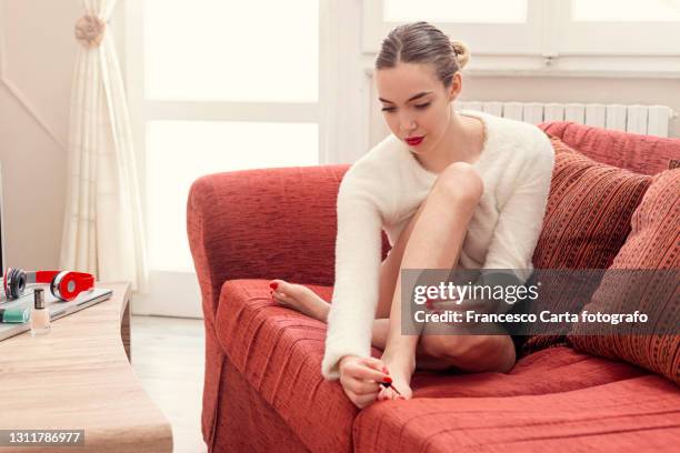 woman applying nail polish to her toenails - painting toenails stock-fotos und bilder