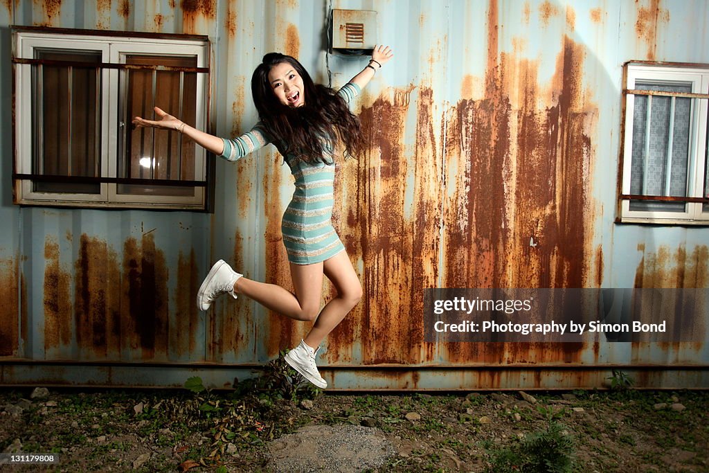 Woman jumping against of rusty wall.