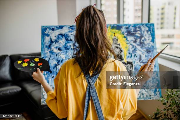 mujer artista trabaja en pintura acrílica abstracta en el estudio de arte - lienzo de artista fotografías e imágenes de stock