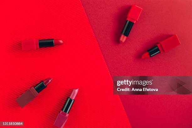 set of various bright red lipsticks on red corrugated and common paper. flat lay style - red lipstick stick stock pictures, royalty-free photos & images