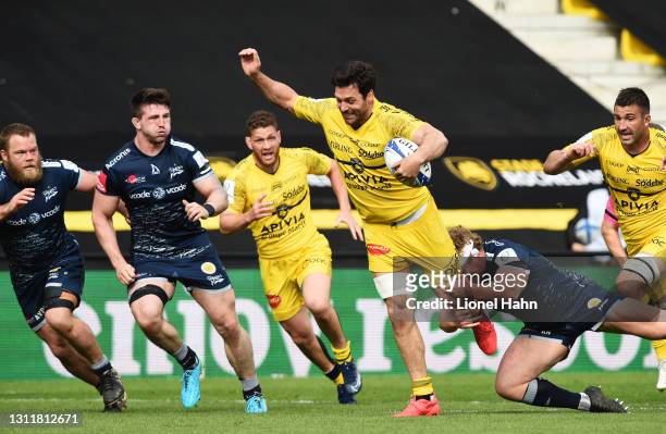 Kevin Gourdon of La Rochelle makes a break as Tom Curry of Sale Sharks looks on during the Quarter Final Champions Cup match between La Rochelle and...