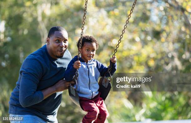 junge mit vater, auf spielplatz schaukel - schaukel mann stock-fotos und bilder