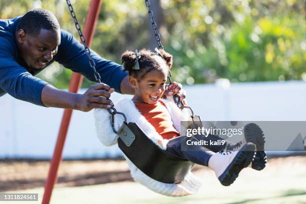 father with daughter on playground swing - using a swing stock pictures, royalty-free photos & images