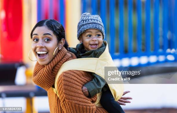 mixed race mother carrying baby on her back - baby carrier stock pictures, royalty-free photos & images