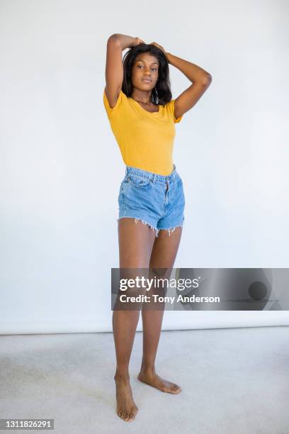 studio portrait of young woman on white backdrop - ladies shorts stockfoto's en -beelden