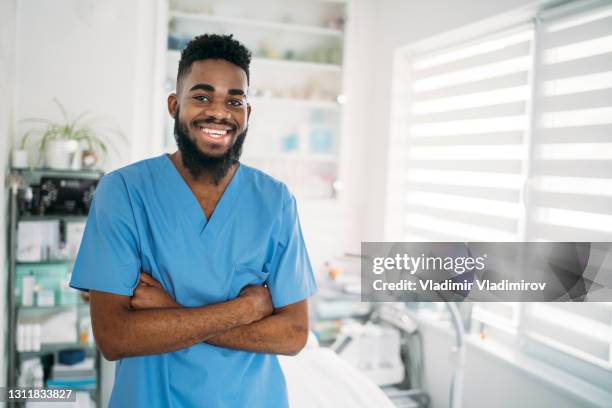 a smiling therapist with his arms crossed standing in his clinic - male arms crossed stock pictures, royalty-free photos & images