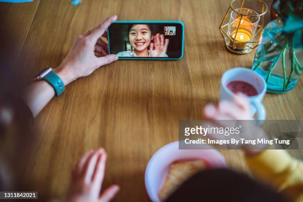 first person perspective of mom & daughter having video call with family while enjoying snacks on a dining table at home - stay at home saying stock pictures, royalty-free photos & images