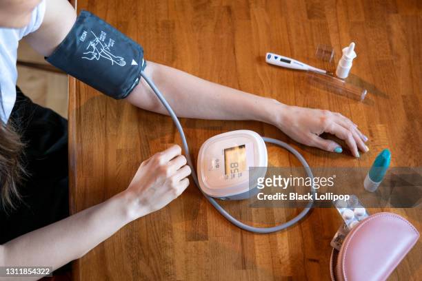 woman measuring blood pressure by herself with a digital pressure gauge at home. - pressure gauge stock pictures, royalty-free photos & images