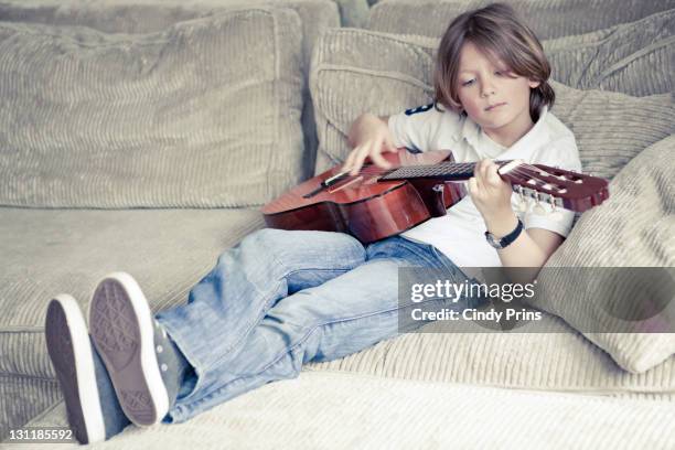 boy playing guitar - pantalon beige photos et images de collection