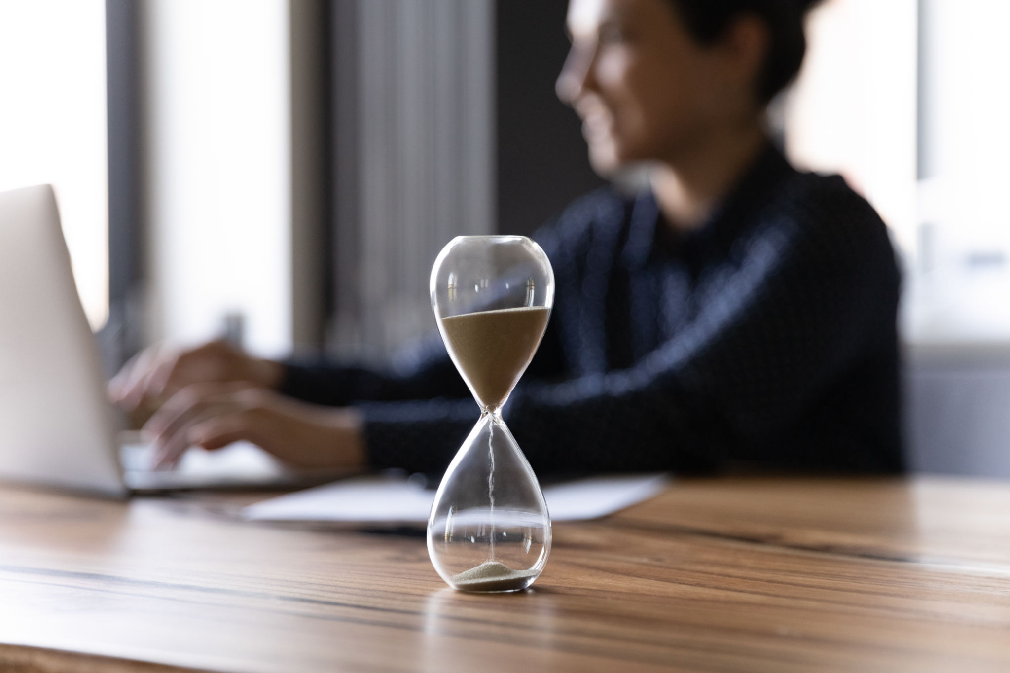 Close up hourglass measuring time, Indian businesswoman working Close up hourglass measuring time, Indian businesswoman working
