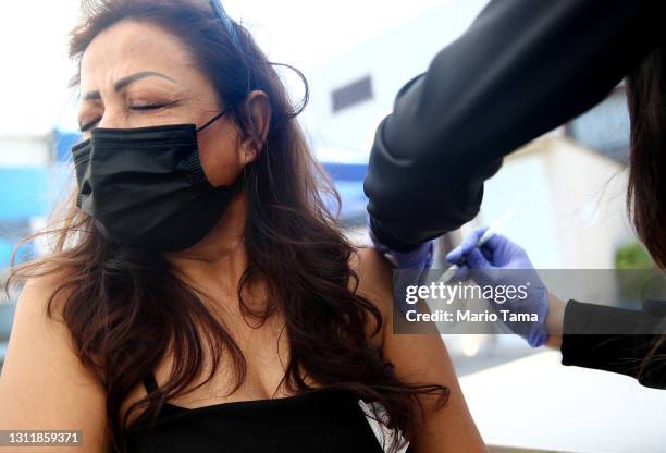 Amparo Del Rayo receives her first dose of the Pfizer COVID-19 vaccine from a health care worker at a clinic targeting Central American Indigenous...